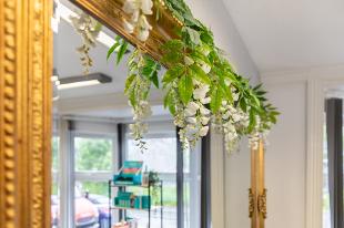 gold mirroe ornate edge with white flowers draped over mirror
